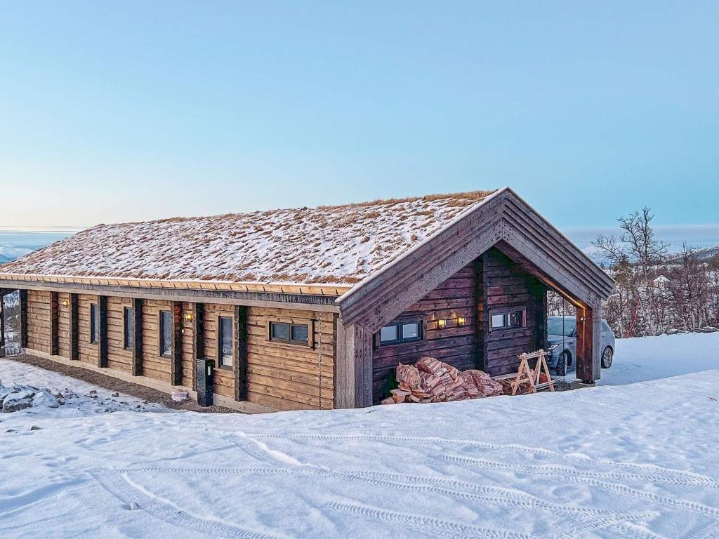 ein Blockhaus mit Schnee auf dem Boden vor dem Haus in der Unterkunft Holiday home Moen in Moen i Målselv