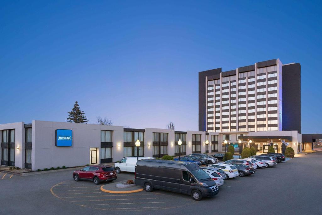 a parking lot with cars parked in front of a building at Travelodge by Wyndham Quebec City Hotel & Convention Centre in Quebec City