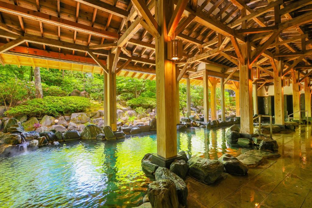 une piscine d'eau dans un bâtiment avec des rochers dans l'établissement TAOYA Akiu, à Sendai