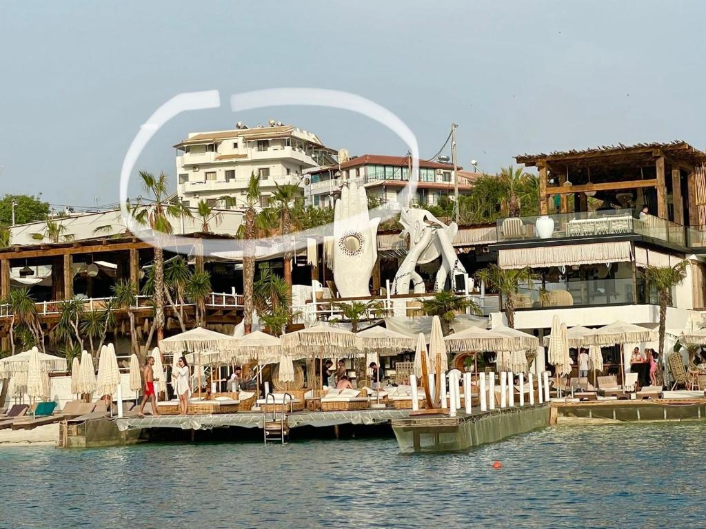 een resort op het water met stoelen en parasols bij Dine Apartments in Ksamil