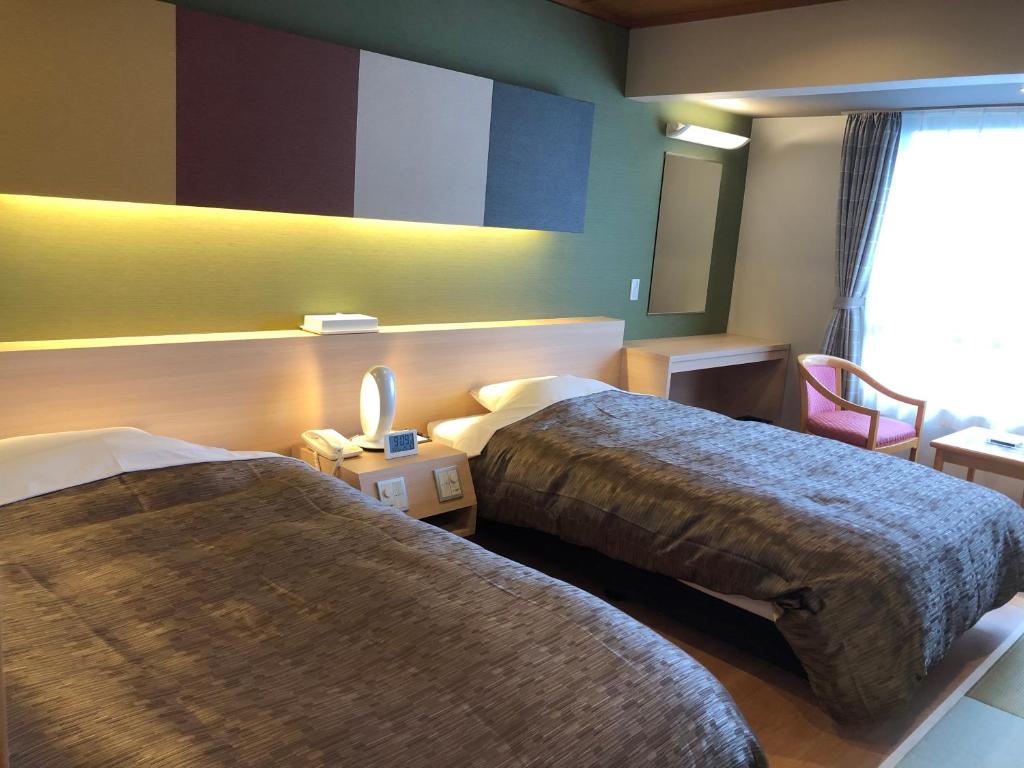 een hotelkamer met 2 bedden en een raam bij Kirishima Hotel in Kirishima