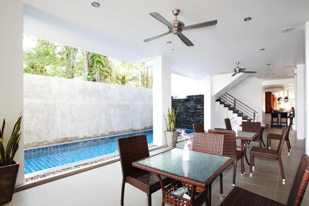 a dining room with a table and chairs and a swimming pool at One World One Home Naiharn Hotel in Rawai Beach