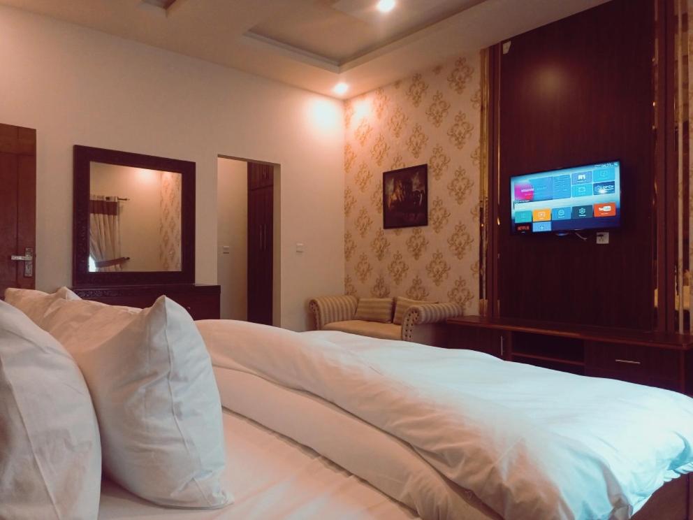 a bedroom with a bed and a flat screen tv at Hotel Grand Home in Murree