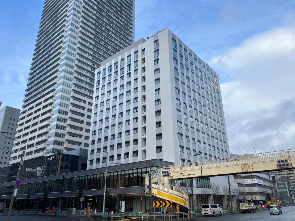 um edifício branco alto com um autocarro em frente em Hotel Emion Sapporo em Sapporo