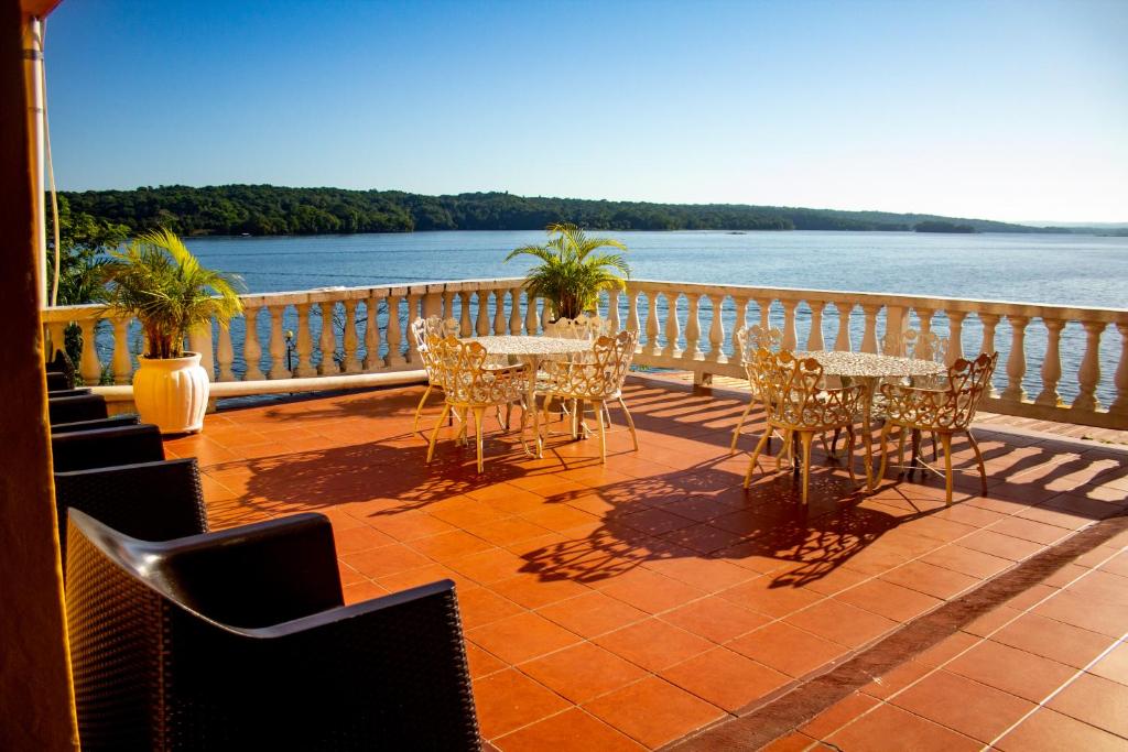 a balcony with tables and chairs and a view of the water at Hotel Villa del Lago in Flores