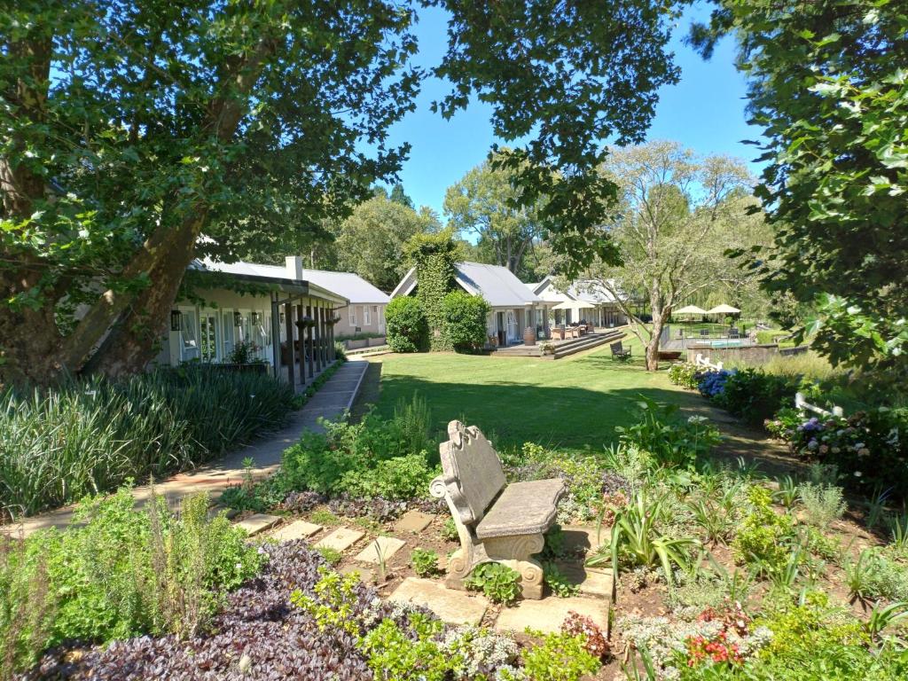 einen Garten mit einer Bank vor einem Gebäude in der Unterkunft Bosch Hoek Golf & Lodge in Balgowan