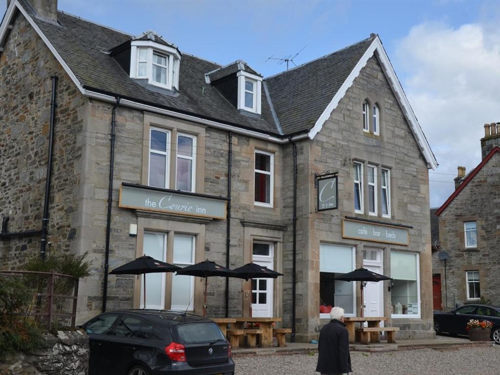 an old stone building with umbrellas in front of it at The Courie Inn in Killin