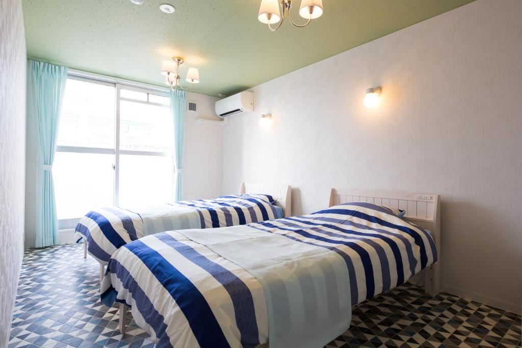 three beds in a room with blue and white stripes at あやきちゲストハウス in Daikōchō