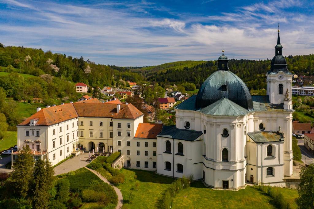 a large white building with a tower on a hill at Zámek Křtiny in Křtiny