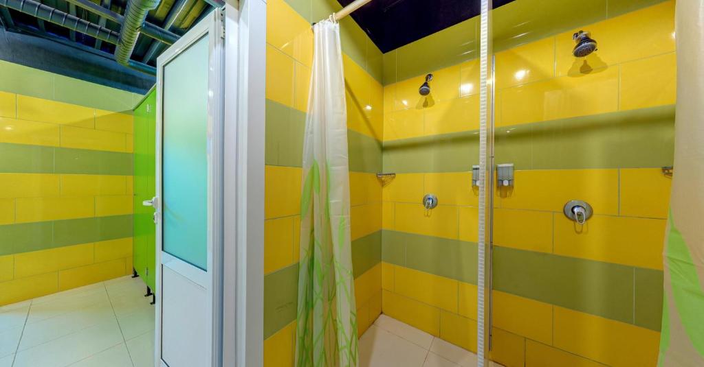 ein Bad mit einer Dusche mit gelben und grünen Streifen in der Unterkunft Green Cube Capsule Hostel in Sofia