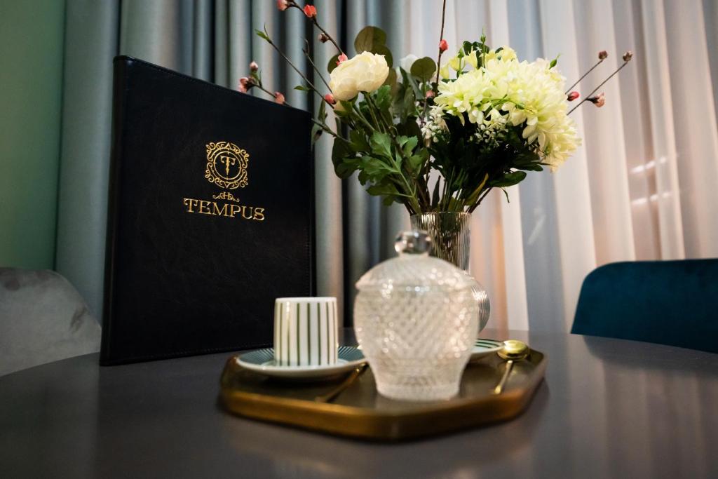 einen Tisch mit einer Vase aus Blumen und einem Teller in der Unterkunft Tempus in Bukarest