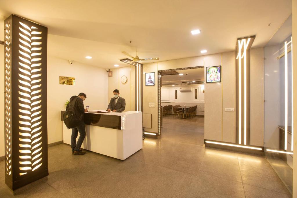 two men standing at a counter in a lobby at Airport Hotel Chanakya in New Delhi