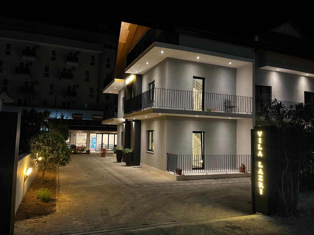 a large white building with a balcony at night at Vila Lazri in Shëngjin