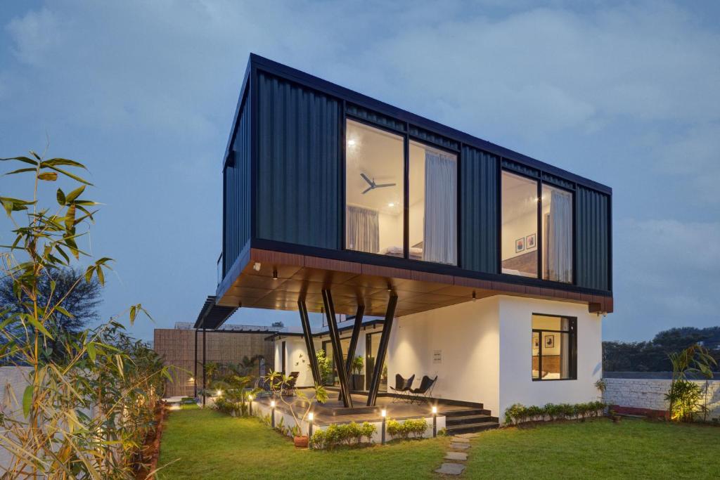 a house with a large glass facade on a lawn at The Hanging Villa - A Luxury Pool Villa in Jaipur in Jaipur