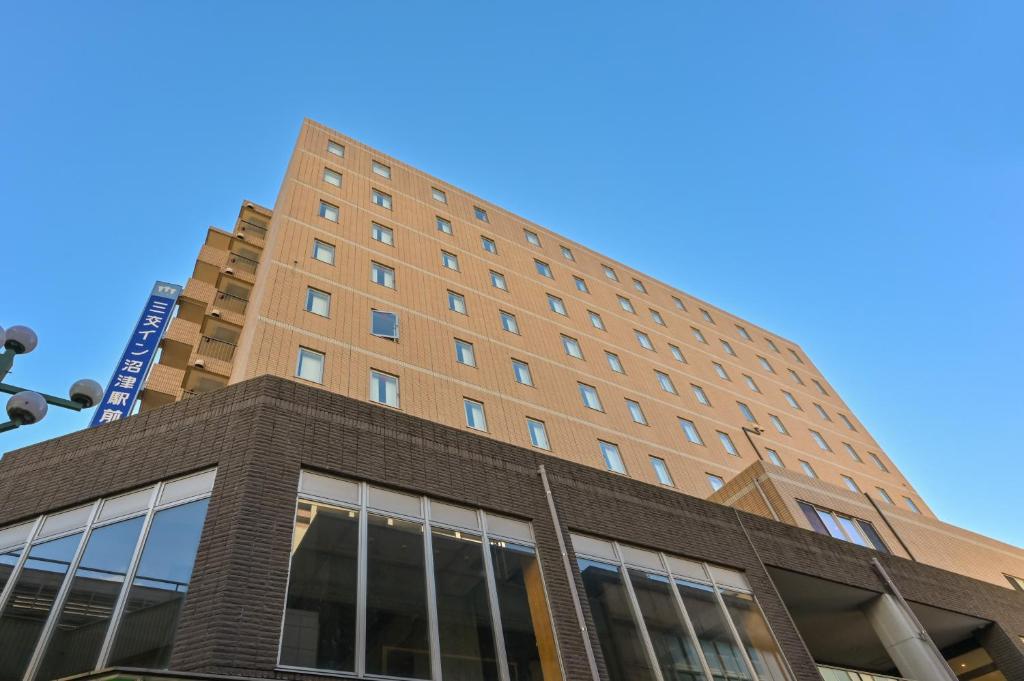 um edifício de tijolos alto com um céu azul ao fundo em Sanco Inn Numazu Ekimae em Numazu