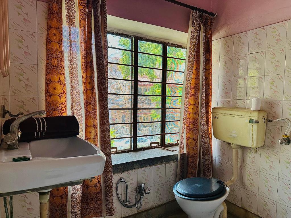 baño con aseo y lavabo y ventana en Jwala Niketan JAIPUR, en Jaipur