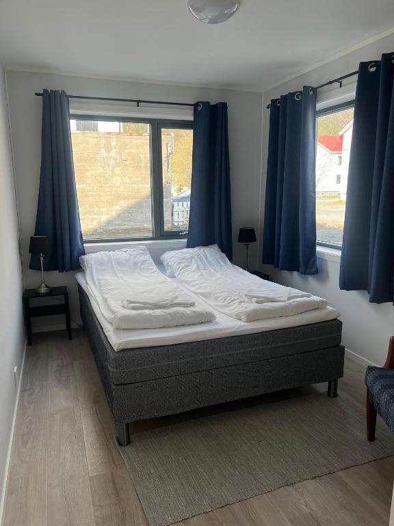 a bedroom with a bed with blue curtains and a window at Mosjøen Romutleie EGEDESGATE 49 in Mosjøen