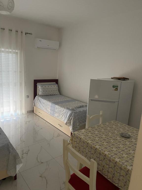 a room with two beds and a table and a refrigerator at Vila Ornela in Shëngjin