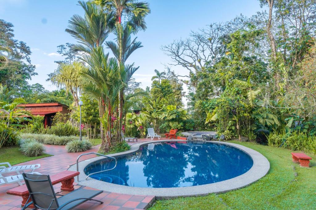 a pool in a yard with chairs and trees at Catarata Eco Lodge in Fortuna