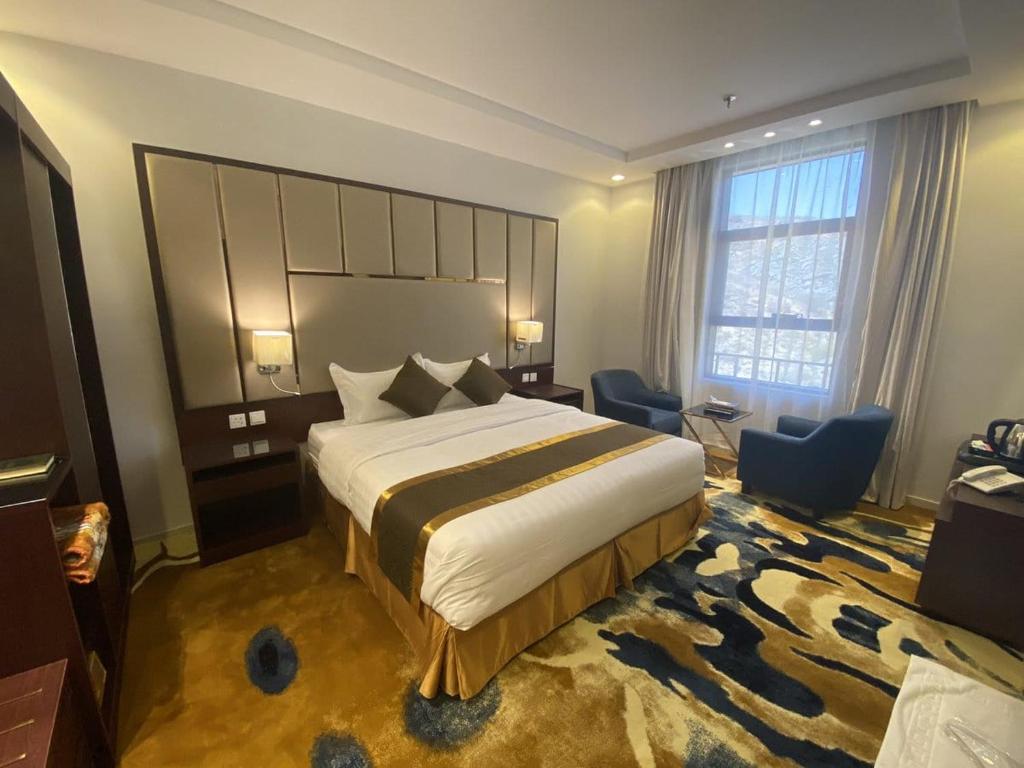 ターイフにあるThikra Hotelのベッドと大きな窓が備わるホテルルームです。