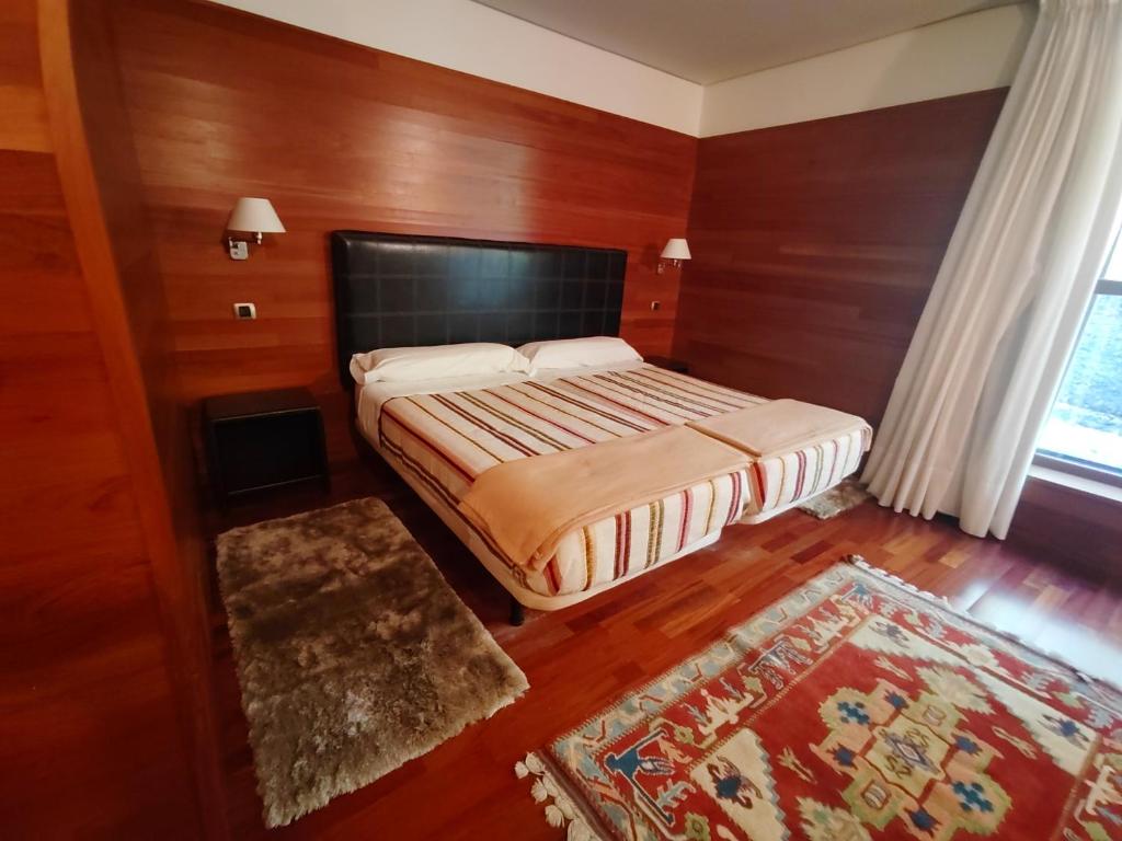 una camera da letto con un letto con pareti in legno e una finestra di KYOMU Resort a Velilla del Río Carrión