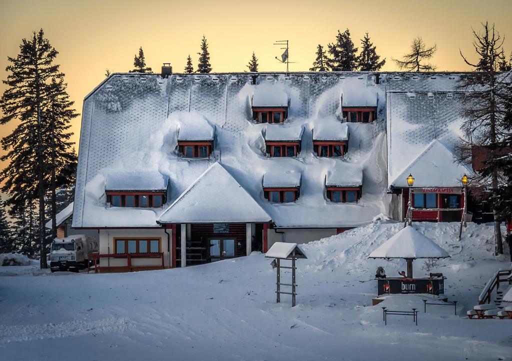 un edificio cubierto de nieve con nieve. en Hotel Krvavec, en Cerklje na Gorenjskem