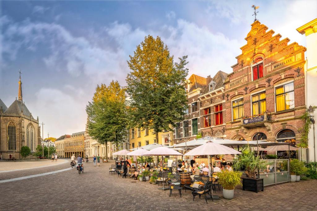 eine Stadtstraße mit Tischen, Stühlen und Gebäuden in der Unterkunft Grand Boutique Hotel-Restaurant Huis Vermeer in Deventer