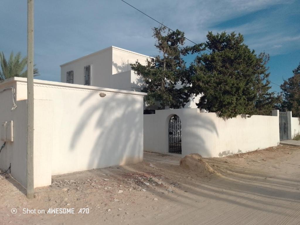 a white building with a gate on a dirt road at La rose 1 in Mezraya