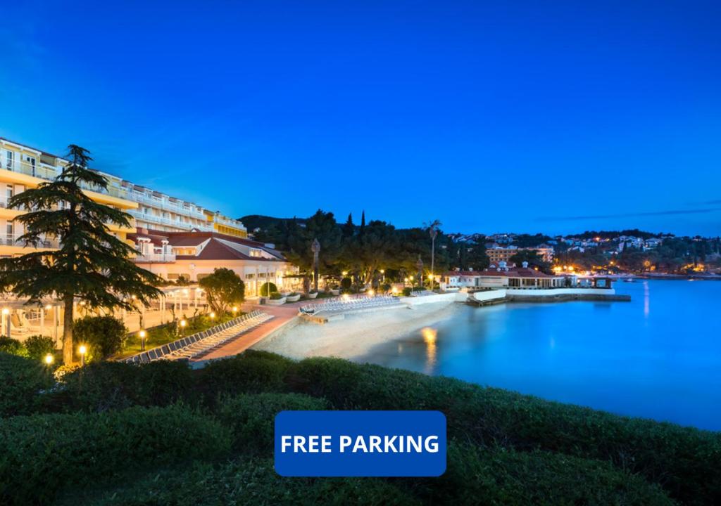 een stad 's nachts met een bord met gratis parkeren bij Remisens Hotel Epidaurus-All inclusive in Cavtat