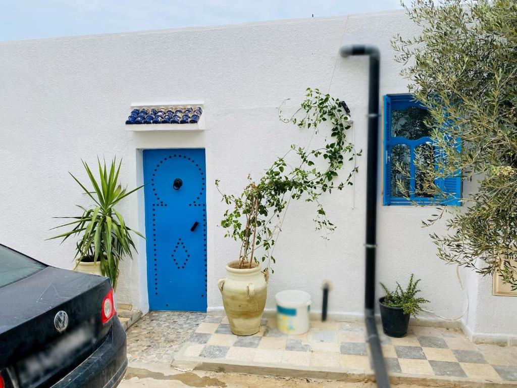 a house with a blue door and a potted plant at Le Refuge Djerbien in Houmt Souk