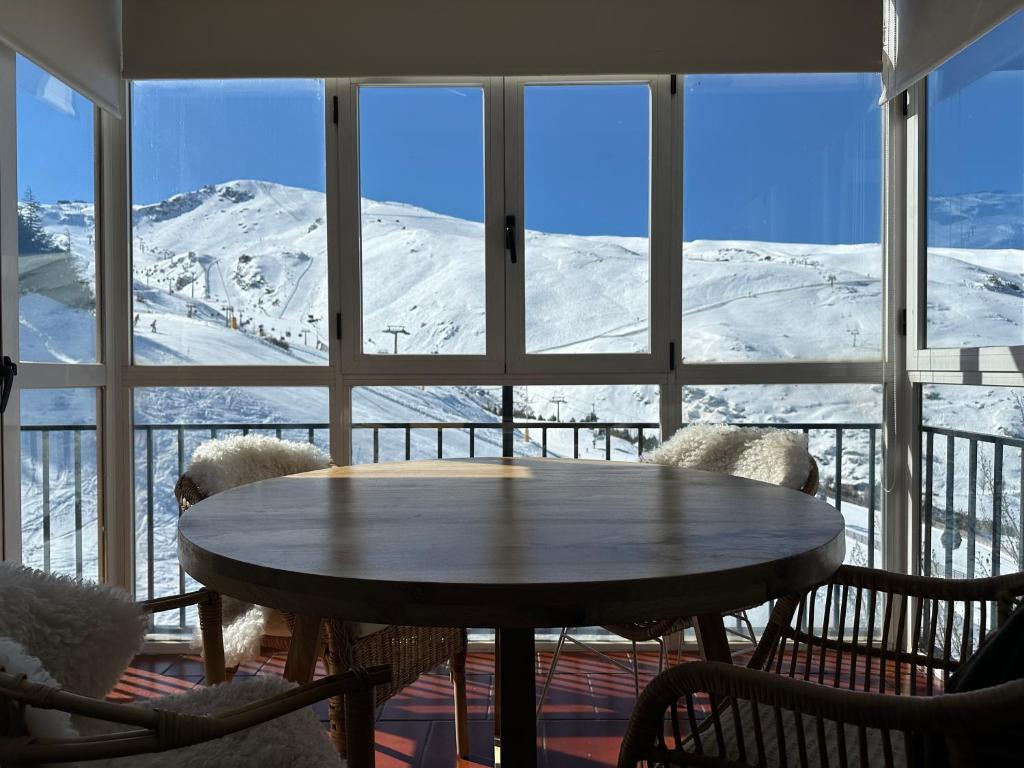 een tafel in een kamer met uitzicht op de met sneeuw bedekte bergen bij Luxury Apartment Zona baja in Sierra Nevada