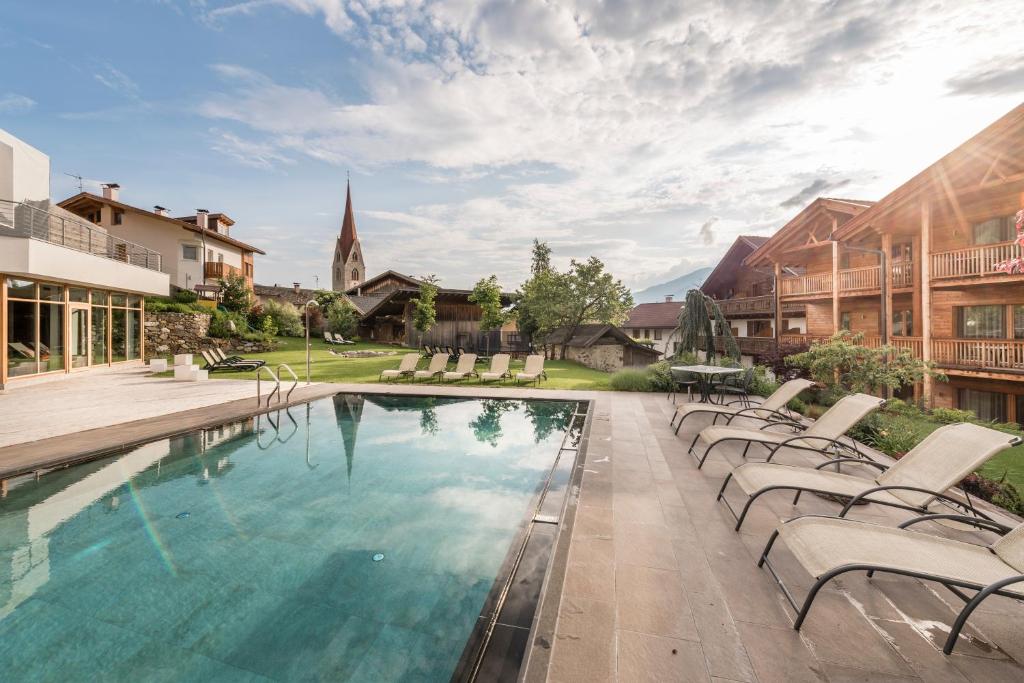 una piscina con sillas y una iglesia en Apartment Lodge Gasserhof, en Bresanona