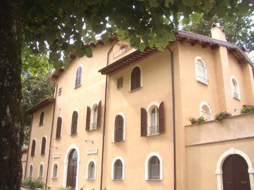 un gran edificio con muchas ventanas y un árbol en La Locanda del Borgo en Pietralunga