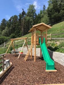 einen Spielplatz mit zwei Schaukeln und einer Rutsche in der Unterkunft Zehrehof in Brixen