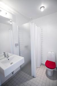 a white bathroom with a toilet with a red seat at Teaterhotellet in Horsens