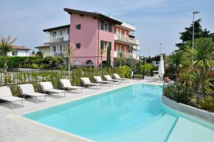 une piscine avec des chaises et un bâtiment rose dans l'établissement Acqua Resorts, à Sirmione