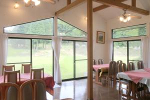 uma sala de jantar com mesas e cadeiras e janelas grandes em Bellbird em Aso