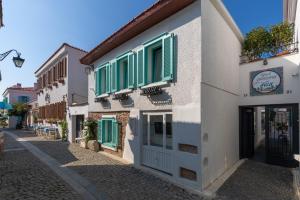 a building with green shutters on a street at Sigacik Gardenya Buti̇k Otel in Siğacık