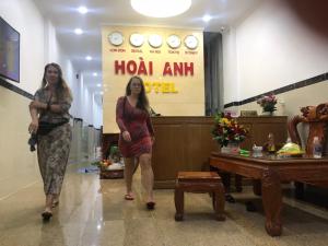 twee vrouwen staan in een kamer met een bord bij Hotel Hoai Anh in Vung Tau