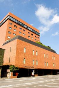 een groot bakstenen gebouw met een straat ervoor bij Hachinohe Grand Hotel in Hachinohe