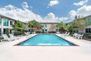 a swimming pool in a courtyard with chairs and a building at Ramada by Wyndham Luling in Luling