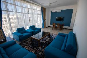 a living room with blue couches and a table at Home Station Hotel in Muscat