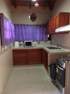 una cocina con armarios de madera y cortinas moradas en Lo de Chawi en Puerto Iguazú