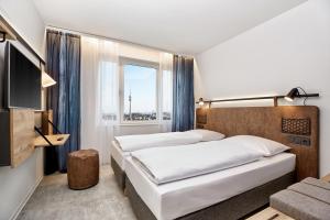 ein Hotelzimmer mit 2 Betten und einem Fenster in der Unterkunft H2 Hotel München Olympiapark in München