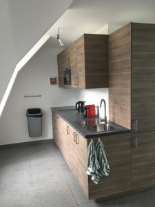 een keuken met houten kasten en een wastafel bij Casa Akuta Airport Flat in Kortenberg