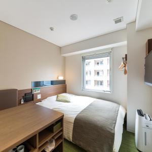 um pequeno quarto com uma cama e uma janela em Super Hotel Premier Hakataeki em Fukuoka