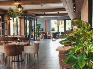 un restaurante con mesas, sillas y plantas en AZZA Hotel - Self Chek-In, en Jesenice