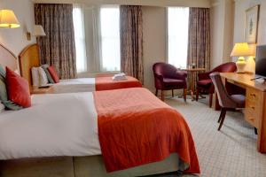 a hotel room with two beds and a desk at Crown & Mitre Hotel in Carlisle