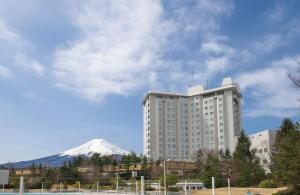 um grande edifício branco com uma montanha ao fundo em Highland Resort Hotel & Spa em Fujiyoshida