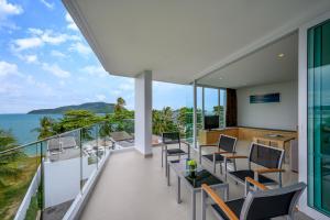 d'un balcon avec des chaises et des tables donnant sur l'océan. dans l'établissement The Beachfront Hotel Phuket, à Rawai Beach